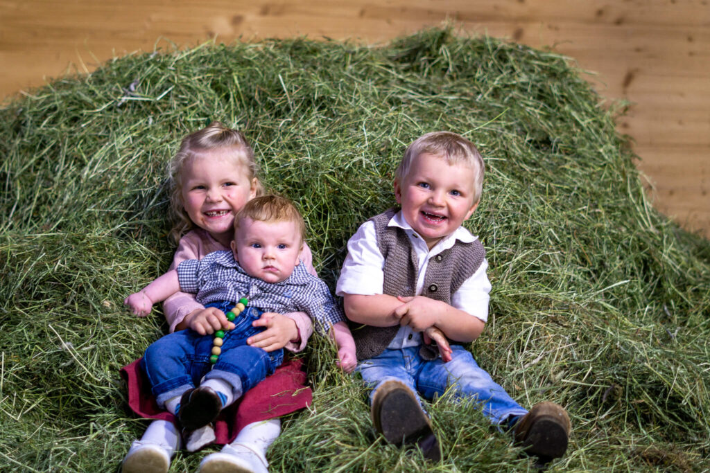 Drei Kinder sitzen im Heu.